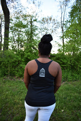Female model wearing a dark grey racerback tank top a small No Egrets Birdcage logo in light grey on the back between the shoulders.