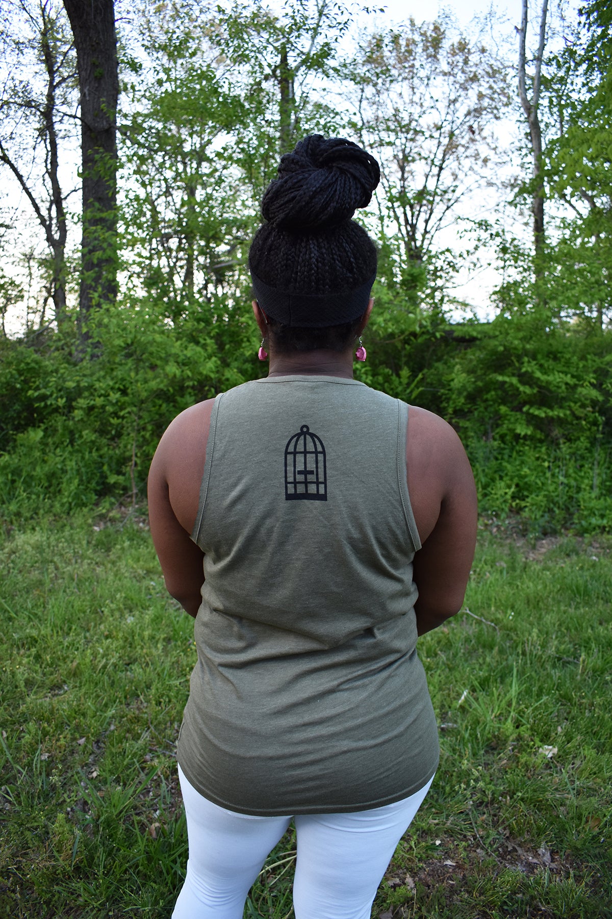 Female model wearing a green tank top a small No Egrets Birdcage logo in black on the back between the shoulders.