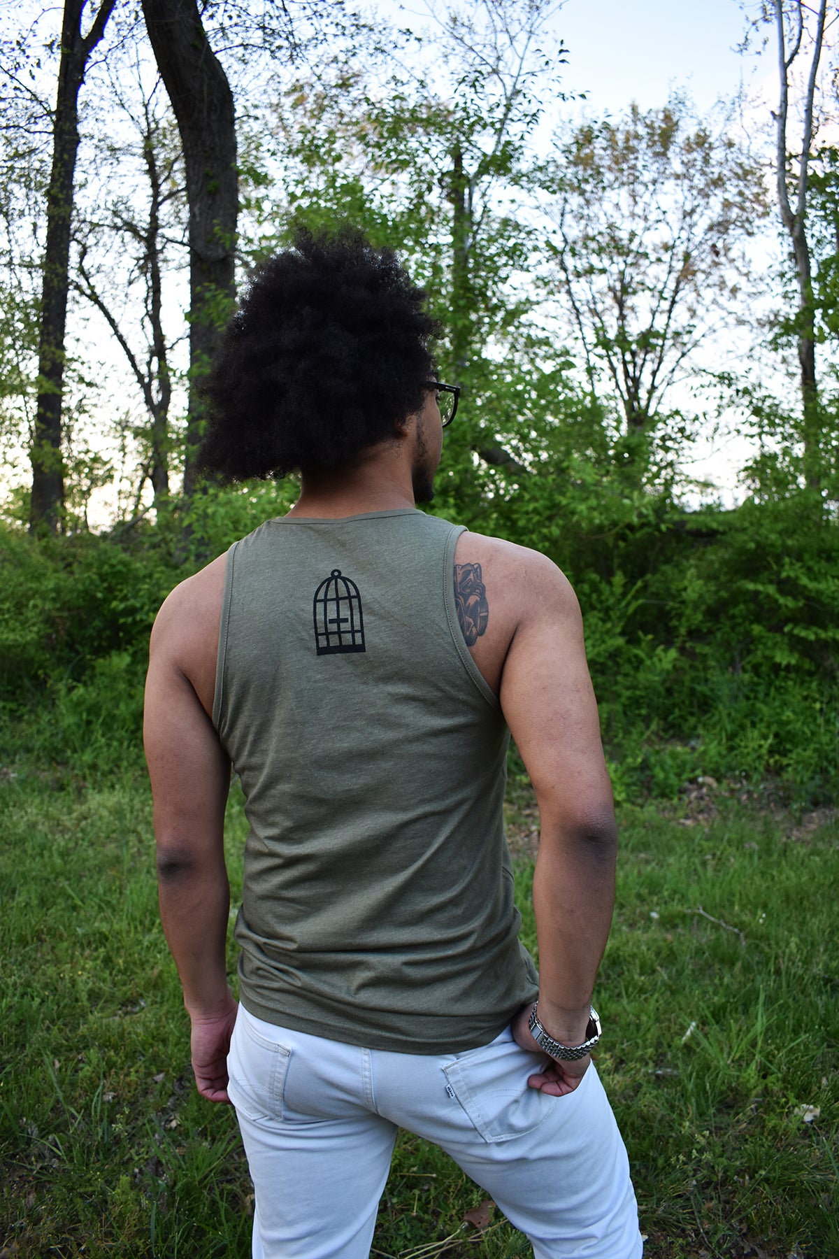 Male model wearing a green tank top a small No Egrets Birdcage logo in black on the back between the shoulders.