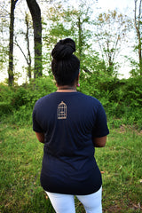 Female model wearing v-neck navy t-shirt with a small, No Egrets Birdcage logo in gold on the back between the shoulders.