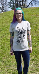 Female model wearing a cream colored t-shirt with Cameron McKnight's Knight design in black on the front.