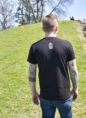 Male model wearing a black t-shirt with a small, No Egrets birdcage logo in white on the back between the shoulders.